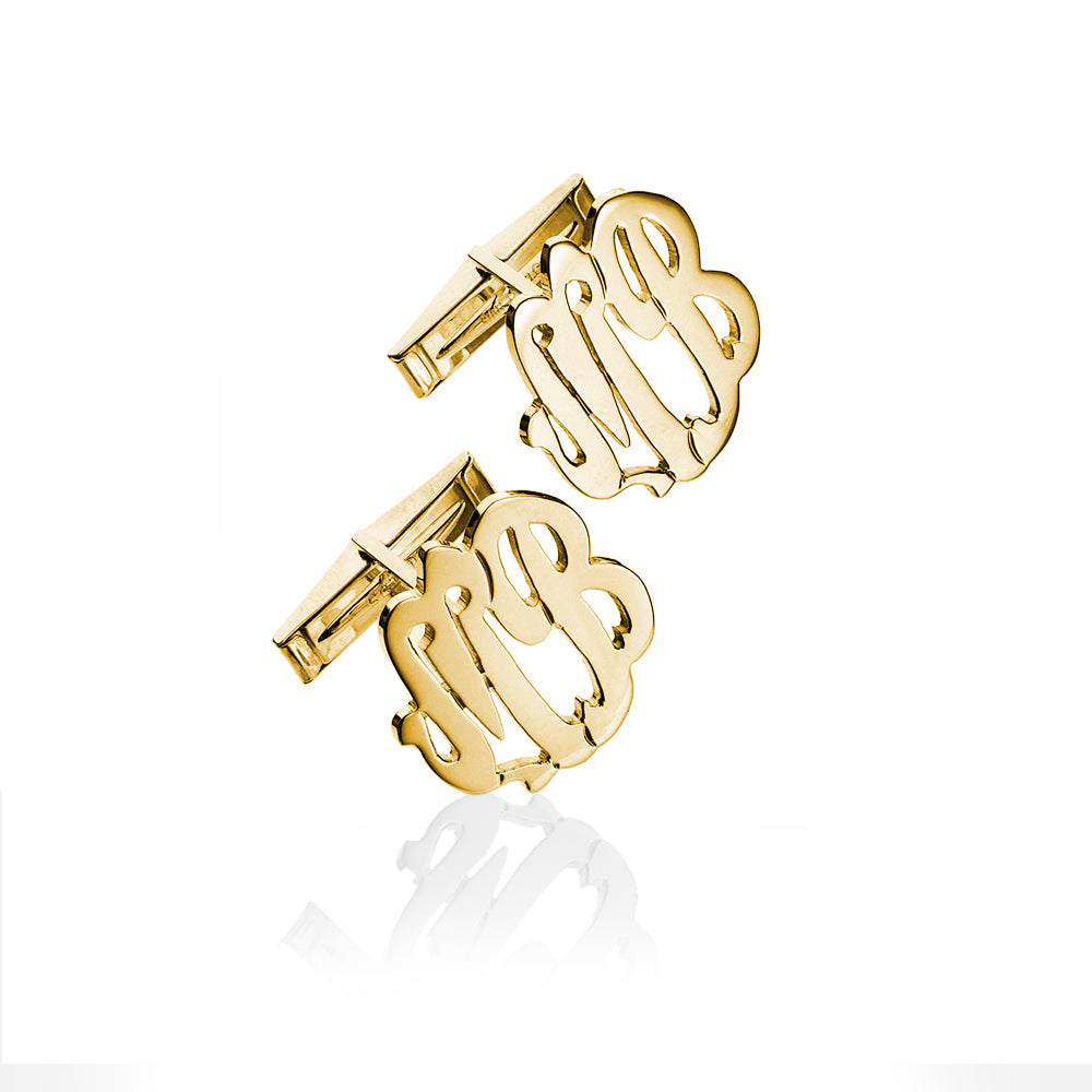 A pair of gold monogram cufflinks featuring the intertwined initials 'MB' in a polished script design, displayed on a clean white background with a soft reflection below.