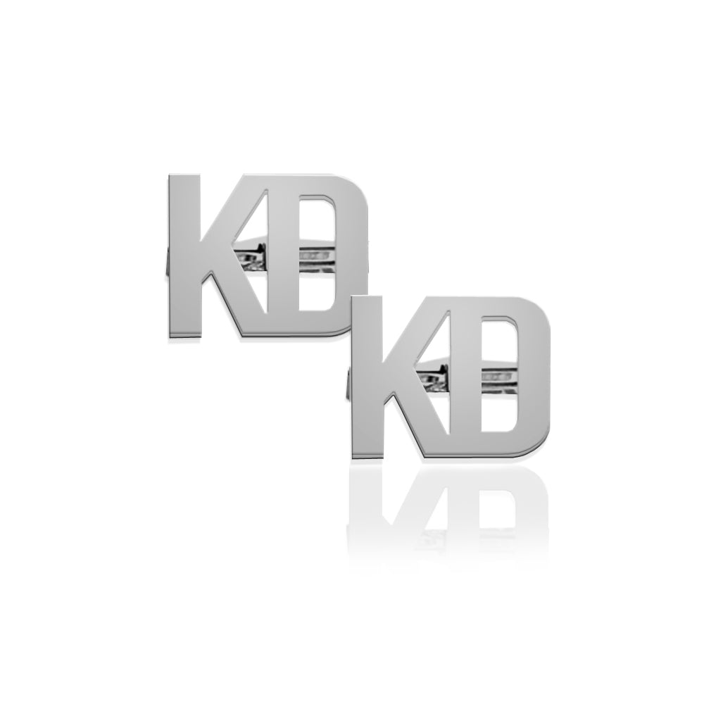 A pair of silver-toned cufflinks featuring the interlocking letters 'KD', displayed on a clean white background with a soft reflection underneath.